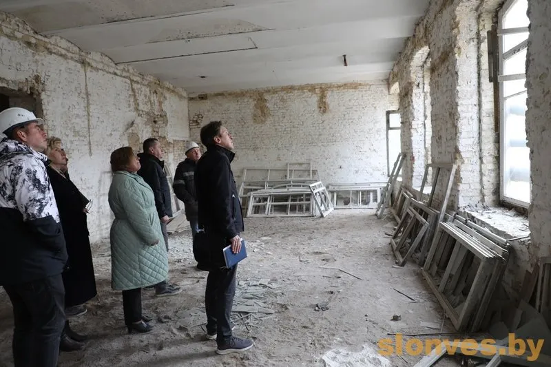 Дом афіцэраў у Слоніме рэканструююць пад духоўны цэнтр Группа людей в полуразрушенной комнате, предположительно бывшем Доме офицеров в Слониме, осматривает помещение с открытыми кирпичными стенами и разбитыми окнами.